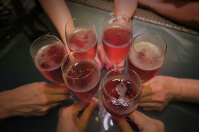 Cropped hands of friends toasting drinks in nightclub