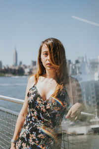 Beautiful woman standing by river in city