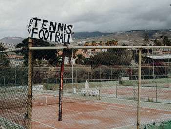 Information sign by fence against sky