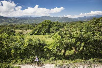 Elderly man pushing bike along dirt road, guatemala.