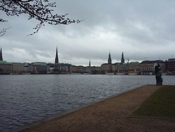 City at waterfront against cloudy sky