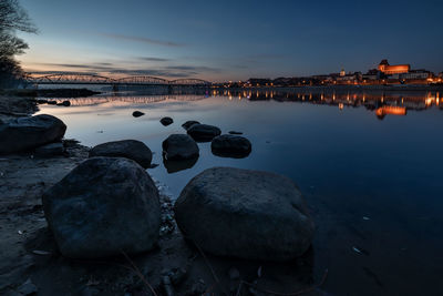 Rocks by sea against sky at sunset