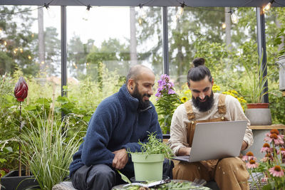 Men using laptop in greenhouse