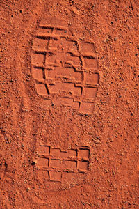 Close-up of shoeprint on sandy field
