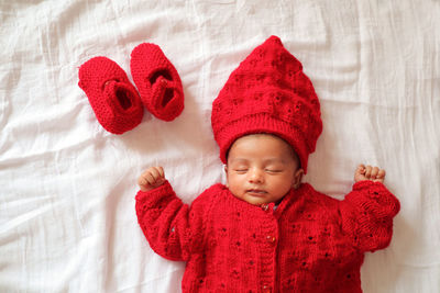 High angle view of baby boy wearing warm clothing sleeping on bed