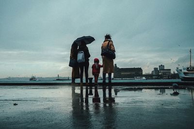 People standing on water against sky during rainy season