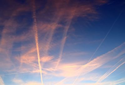 Low angle view of vapor trail in sky during sunset