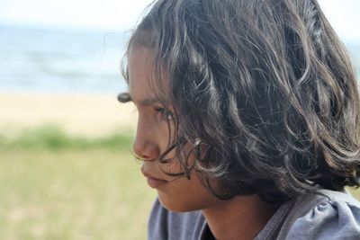 Close-up side view of thoughtful young woman looking away at beach