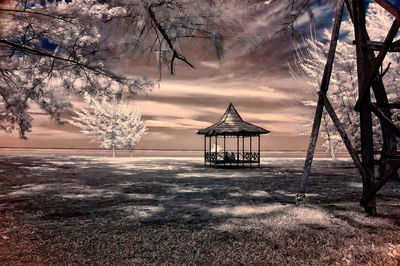 Lifeguard hut on land against sky during sunset