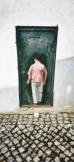 Rear view of man standing by door of building