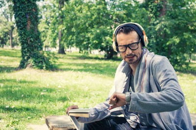 Mature man checking time while sitting in park