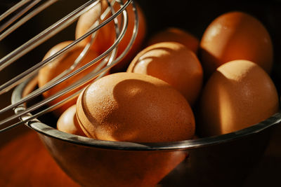 Silver bowl with brown chicken eggs on wood table