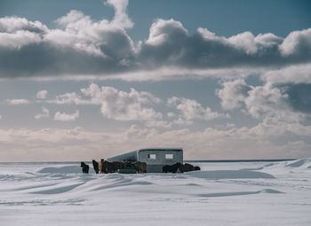 Built structure on snow covered field against sky