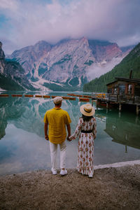 Rear view of woman standing by lake against mountains