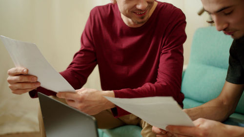 Midsection of couple holding paper