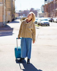 Senior 60s woman with blue suitcase traveling alone after retirement