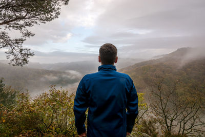 Rear view of hiker standing on mountain against sky during sunset