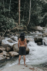 Rear view of shirtless man standing in water