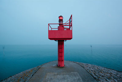 Information sign by sea against clear blue sky