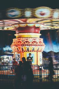 People at illuminated amusement park at night