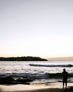 Silhouette man standing on beach against clear sky