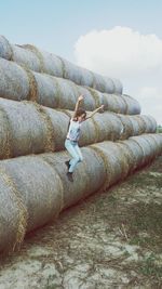 Woman with arms raised on field against sky