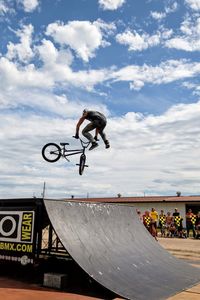 Low angle view of man jumping against sky