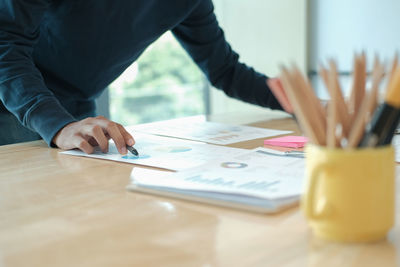 Midsection of businessman analyzing data at table in office