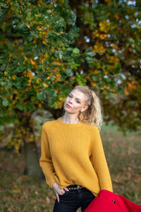 Portrait of a smiling young woman standing against trees