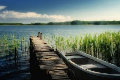 Pier over calm lake against blue sky