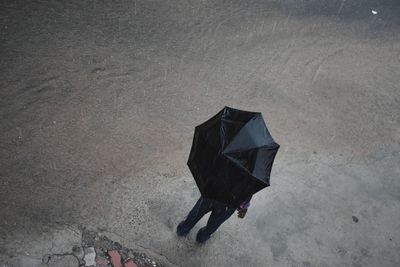 High angle view of man with umbrella standing on road during rainy season