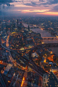 Aerial view of illuminated city buildings against sky at sunset