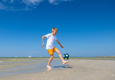 Full length of boy on beach against sky