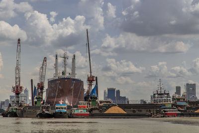 Cranes at harbor against sky