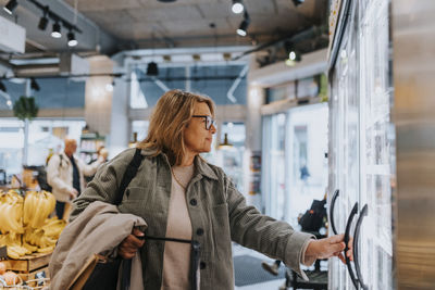 Smiling senior woman doing shopping in supermarket