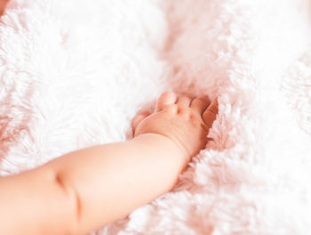 Cropped hand of baby on bed