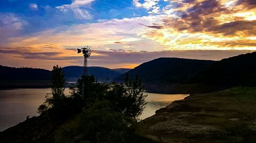 Silhouette trees by lake against sky during sunset