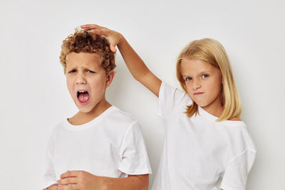 Portrait of sibling fighting against white background