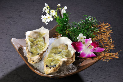 Close-up of oysters with flowers in bowl served on table