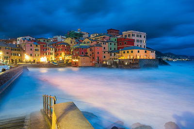 Illuminated buildings by city against sky at dusk