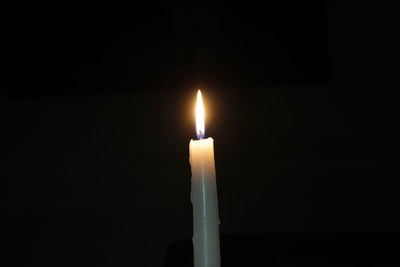 Close-up of lit candle in dark room