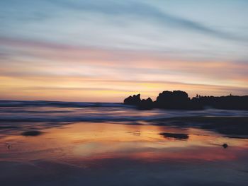 Scenic view of sea against dramatic sky during sunset