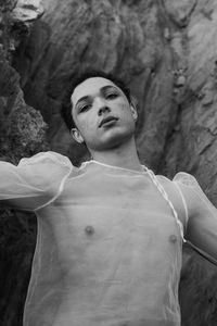 Young male with  androgynous look shot outdoor in black and white with rocks in background.