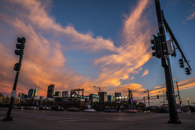 Street by buildings against sky during sunset