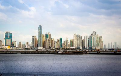 Sea by buildings against sky in city