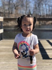 Portrait of cute girl holding fishing rod standing outdoors