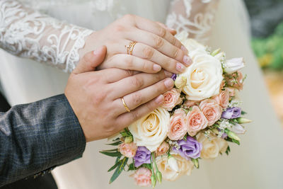 The bride and groom got married and showed their wedding rings over the bride's delicate bouquet