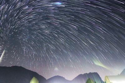 Low angle view of star trails over mountains