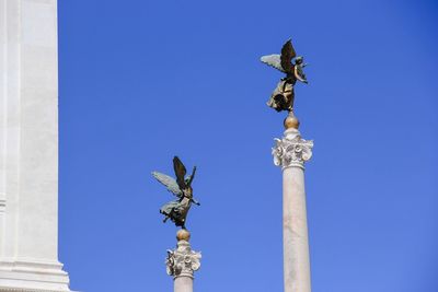 Low angle view of columns against clear blue sky on sunny day