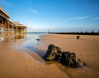 Sandy beach lit by the low sun with a victorian pier in the background